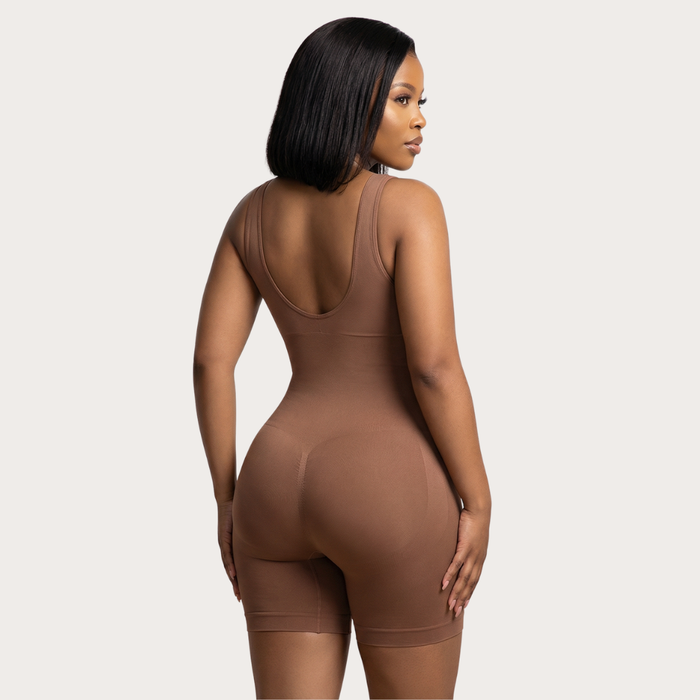 Woman wearing a brown bodysuit against a plain background